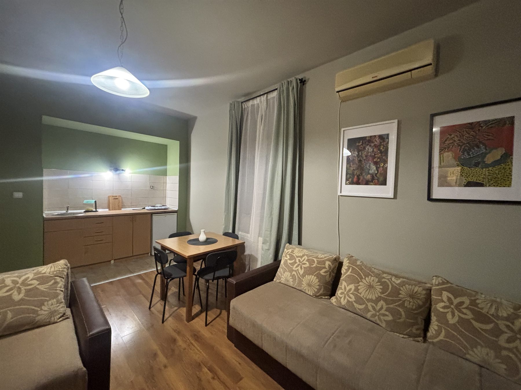 Dnevni boravak apartmana sa sofom, trpezarijskim stolom i klima uređajem
